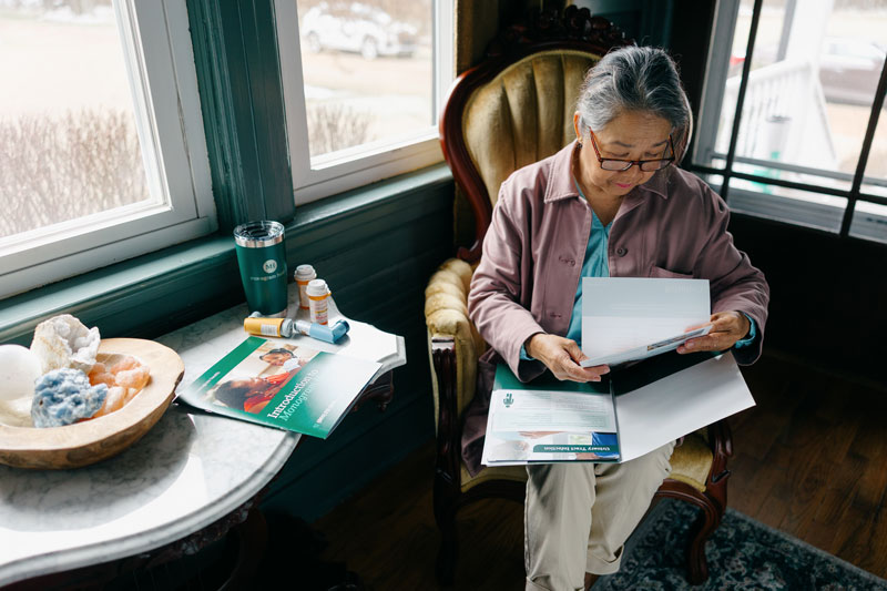 Monogram Health patient reviewing information in a folder sitting in a chair in living room
