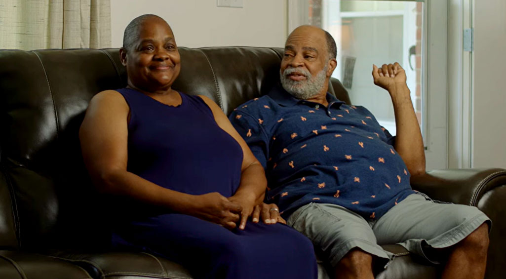 Husband and wife sitting on a couch talking about their Monogram Health experience.