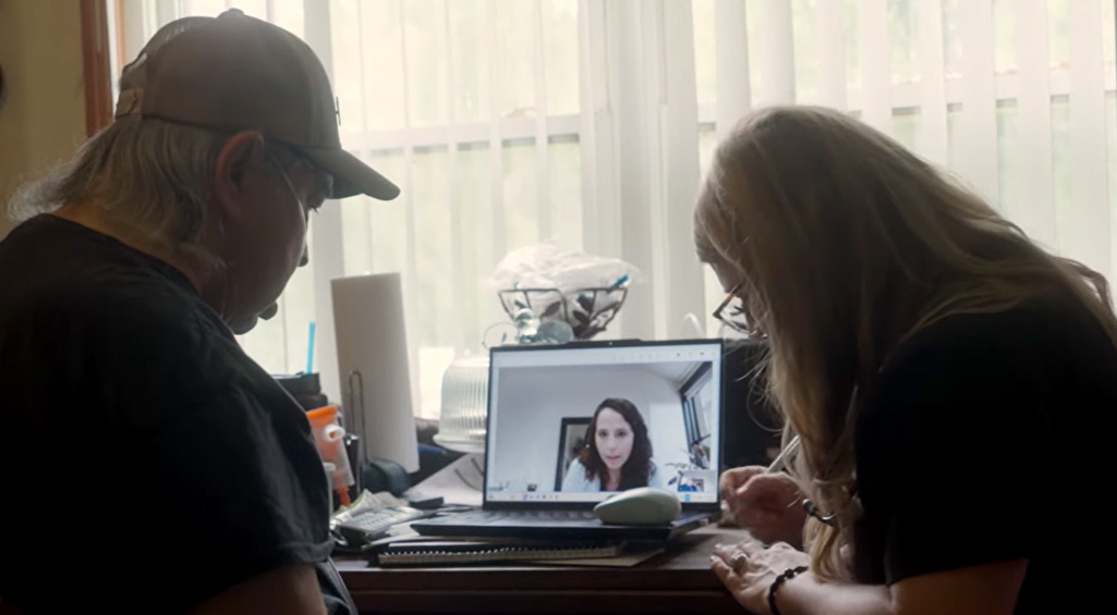 Monogram Health patient sitting at their kitchen table with a Monogram Health APP on a telehealth video call with a Monogram Health clinician.