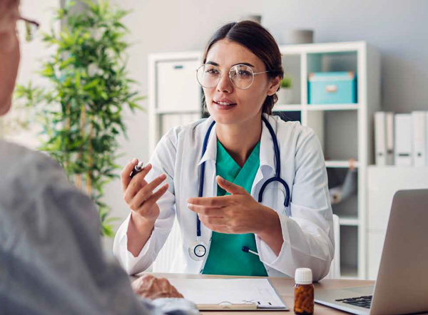Physician speaking with a business professional at a desk.