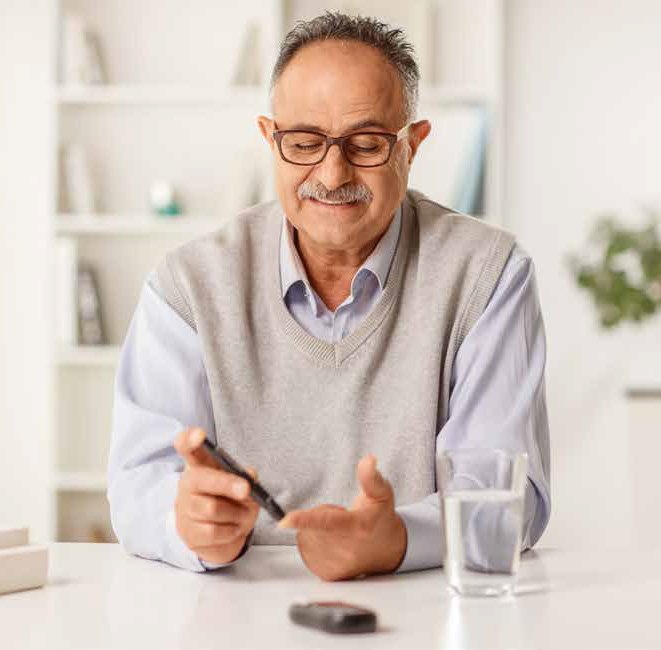 Man sitting at a table or desk with his phone and a glass of water, smiling.
